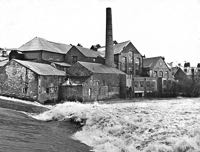 High water rages over the leat, beneath the old Head Wier Mill